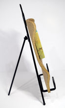 Load image into Gallery viewer, Backyard Bluebird painting by Pat Cross mounted in a handbuilt and kiln fired stoneware frame resting on a black metal easel facing to show profile.