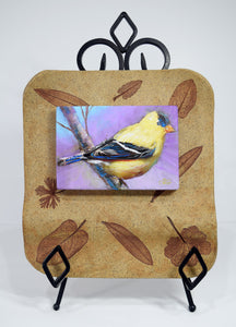 Alluring Goldfinch original painting by Pat Cross mounted in a handbuilt kiln fired stoneware frame and resting on a black metal easel.