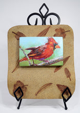 Load image into Gallery viewer, Forest Ruby Cardinal original painting by Pat Cross mounted on a hand built and kiln fired stoneware frame resting on a black metal easel.
