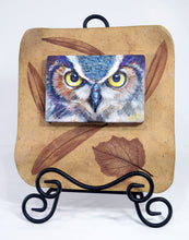 Load image into Gallery viewer, Night Owl painting by Pat Cross mounted in a hand built and kiln fired stoneware frame set on a black metal easel facing front.
