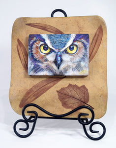 Night Owl painting by Pat Cross mounted in a hand built and kiln fired stoneware frame set on a black metal easel facing front.