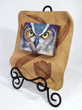Load image into Gallery viewer, Night Owl painting by Pat Cross mounted in a hand built and kiln fired stoneware frame set on a black metal easel facing left.
